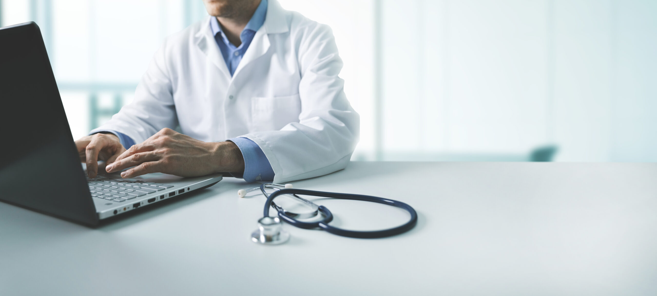 online medical consultation - doctor working on laptop computer in clinic office. copy space